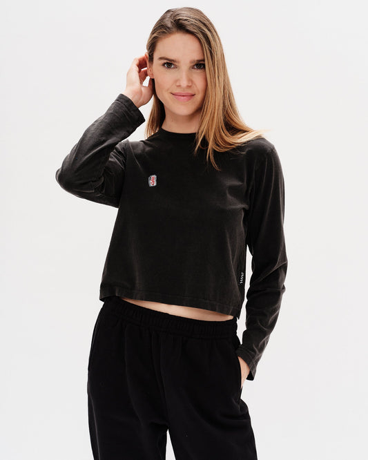 Woman wearing a black long-sleeve crop top with an embroidered diet coke design