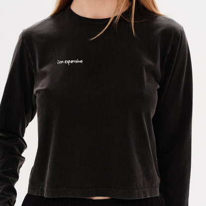 Woman wearing a black long-sleeve t-shirt with an I'm expensive embroidery