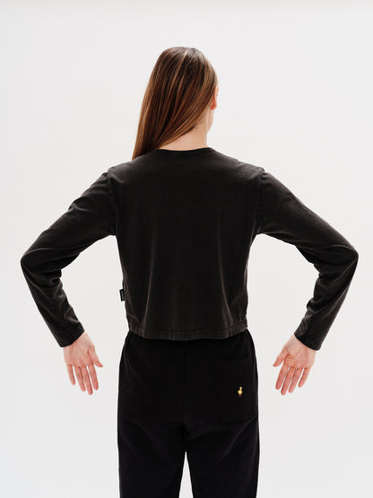 Woman wearing a black long-sleeve crop top with a Martini design embroidery