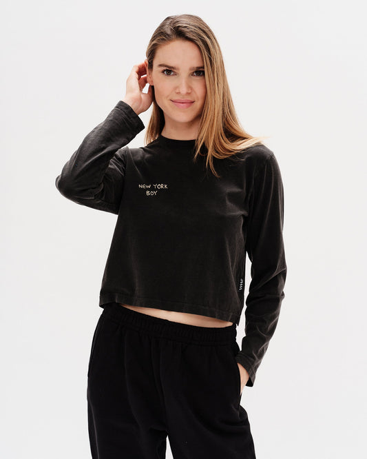 Woman wearing a black long-sleeve crop top with 'New York Boy' embroidery