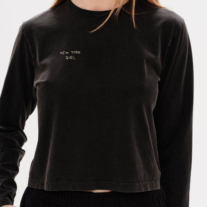 Woman wearing a black long-sleeve t-shirt with 'New York Girl' embroidery