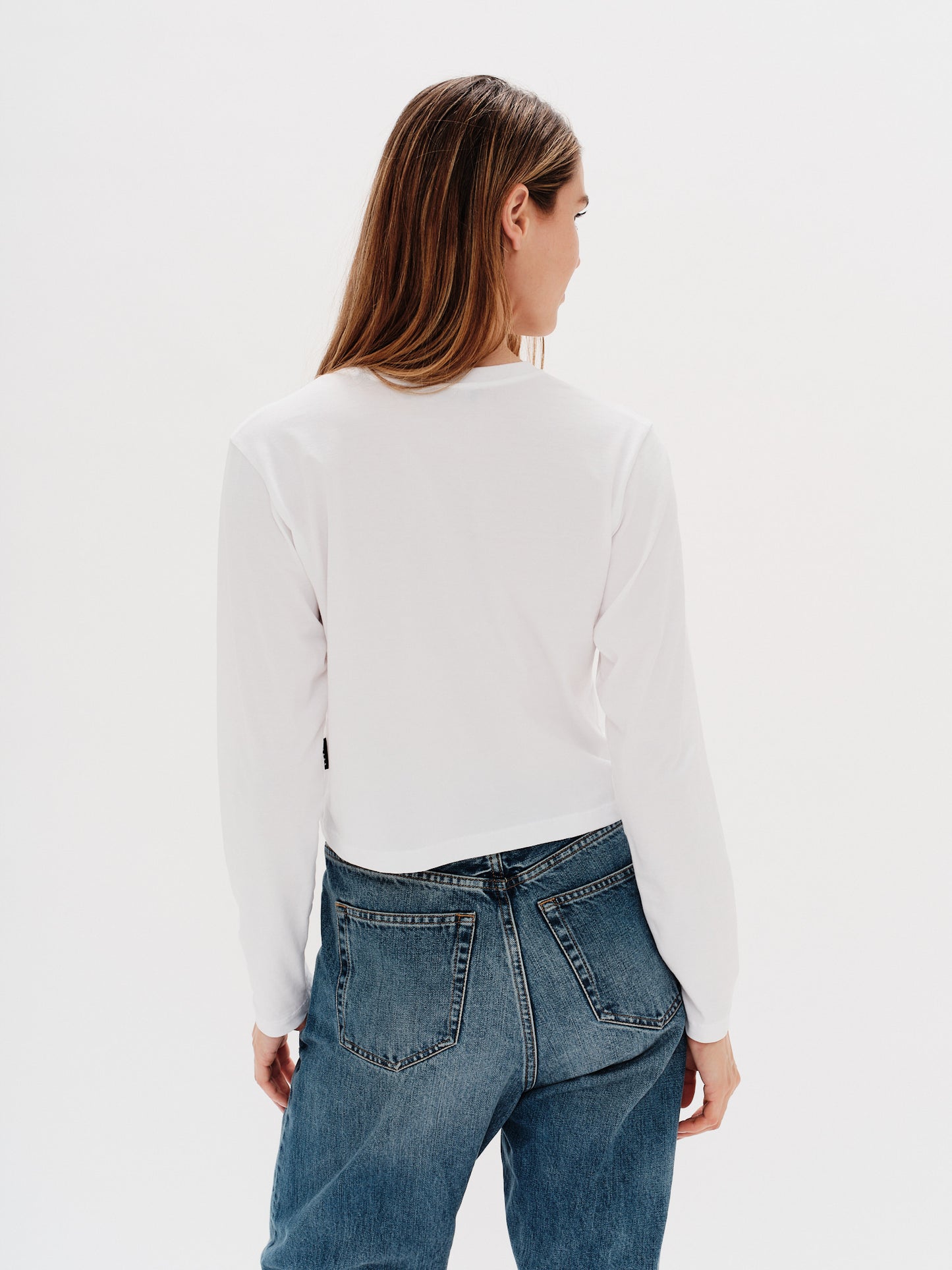 Woman wearing a white long-sleeve t-shirt with 'New York Girl' embroidery