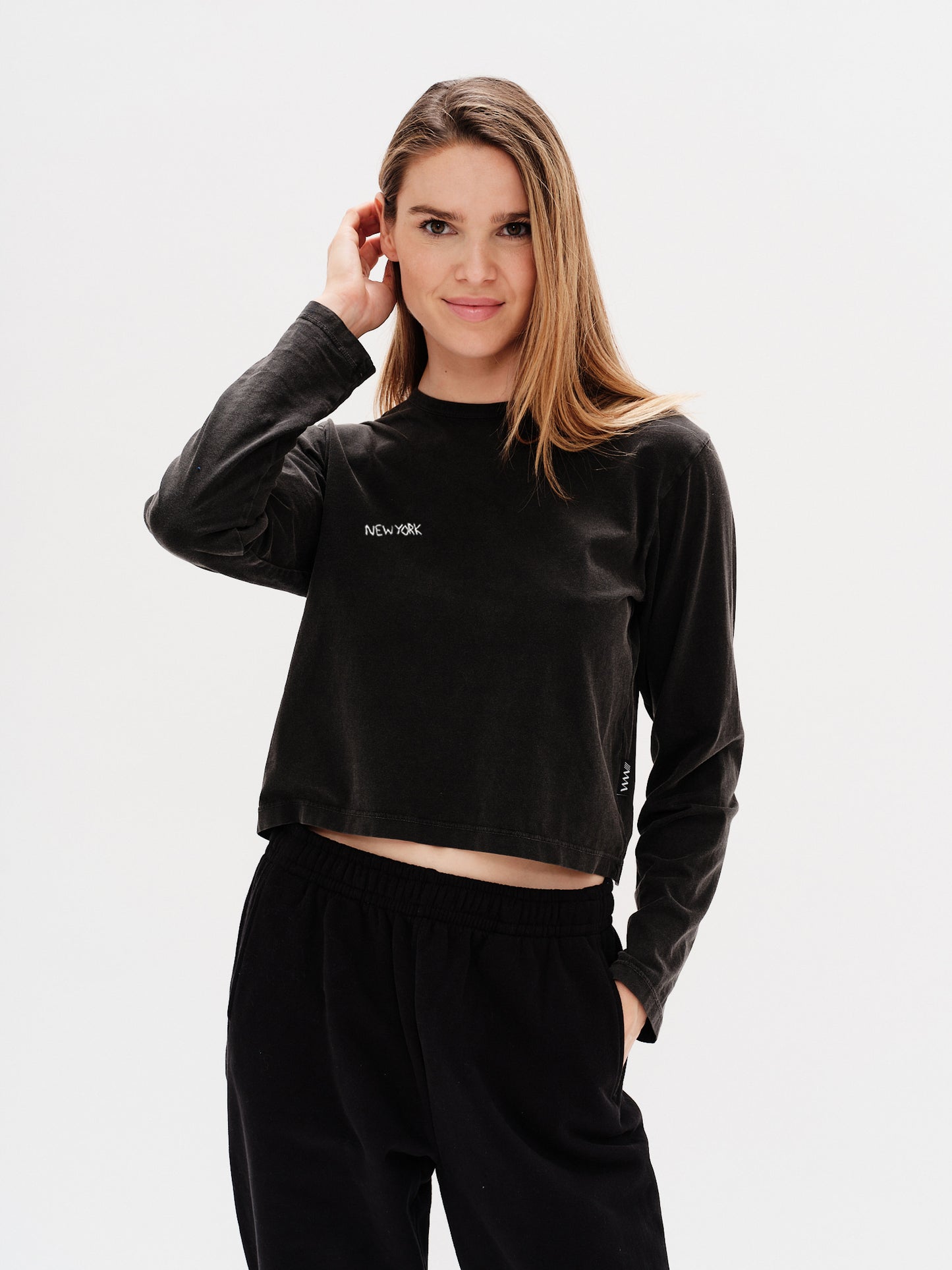 Woman wearing a black long-sleeve crop top with a New York embroidery