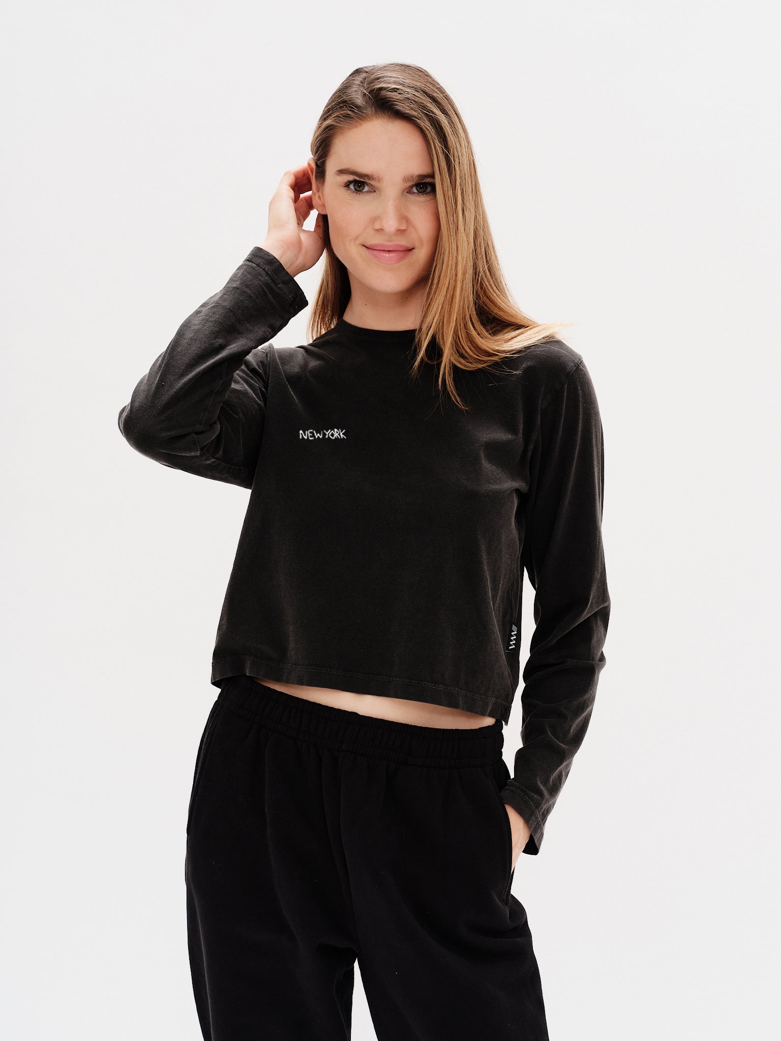 Woman wearing a black long-sleeve crop top with a New York embroidery