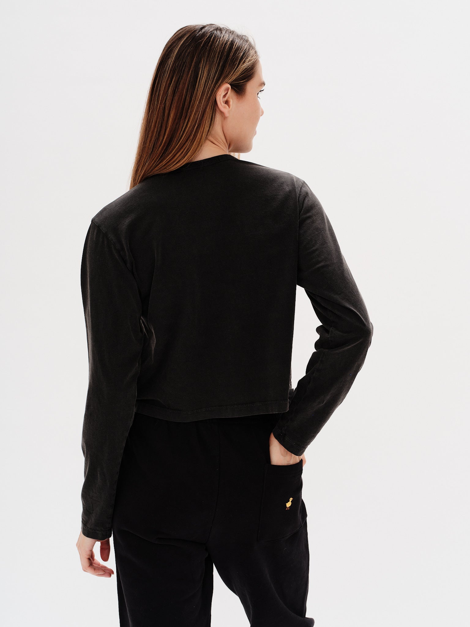 Woman wearing a black long-sleeve crop top with a New York embroidery