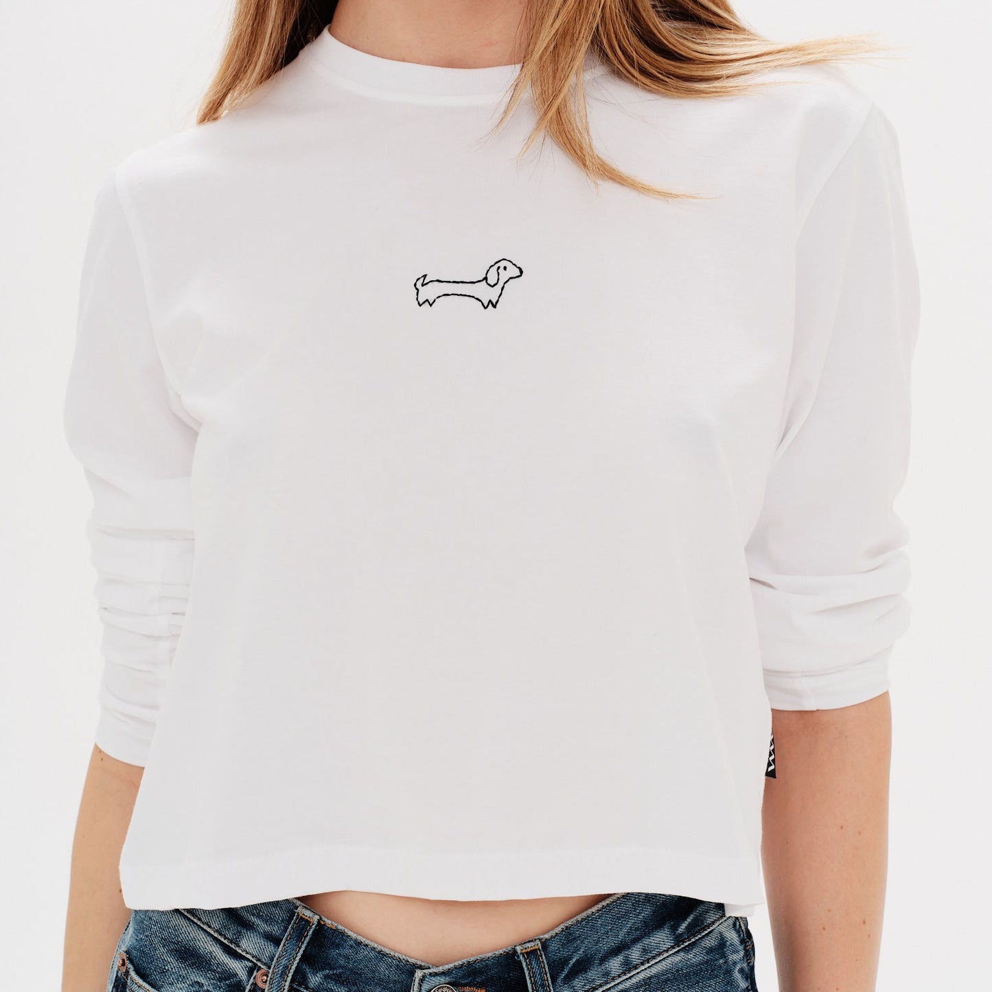 Woman wearing a white long-sleeve t-shirt with a wiener dog embroidery