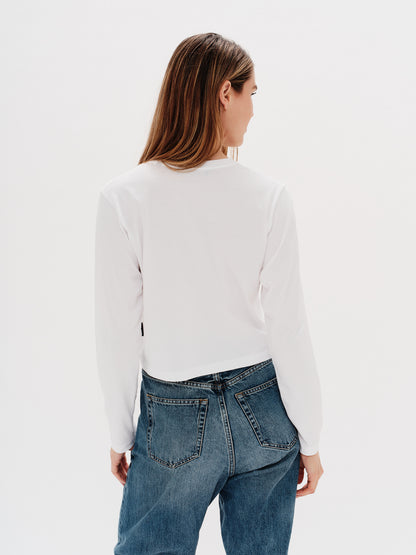 Woman wearing a white long-sleeve crop with a long hair wiener dog design embroidery