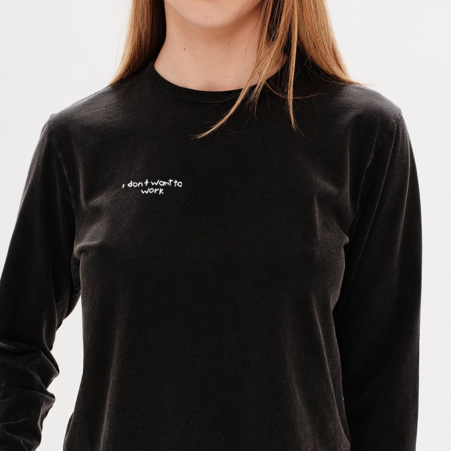 Woman wearing a black long-sleeve crop top with an I don't want to work embroidery