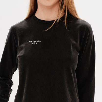 Woman wearing a black long-sleeve crop top with an I don't want to work embroidery