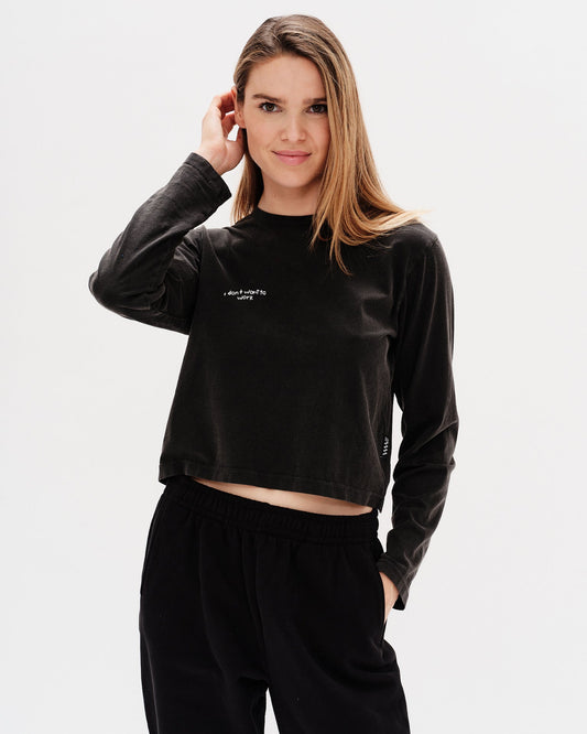 Woman wearing a black long-sleeve crop top with an I don't want to work embroidery