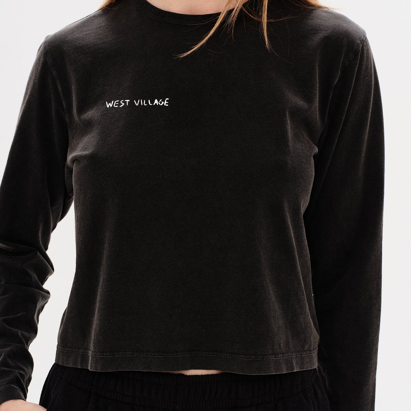 Woman wearing a black long-sleeve t-shirt with a west village embroidery