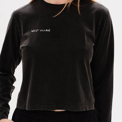 Woman wearing a black long-sleeve t-shirt with a west village embroidery