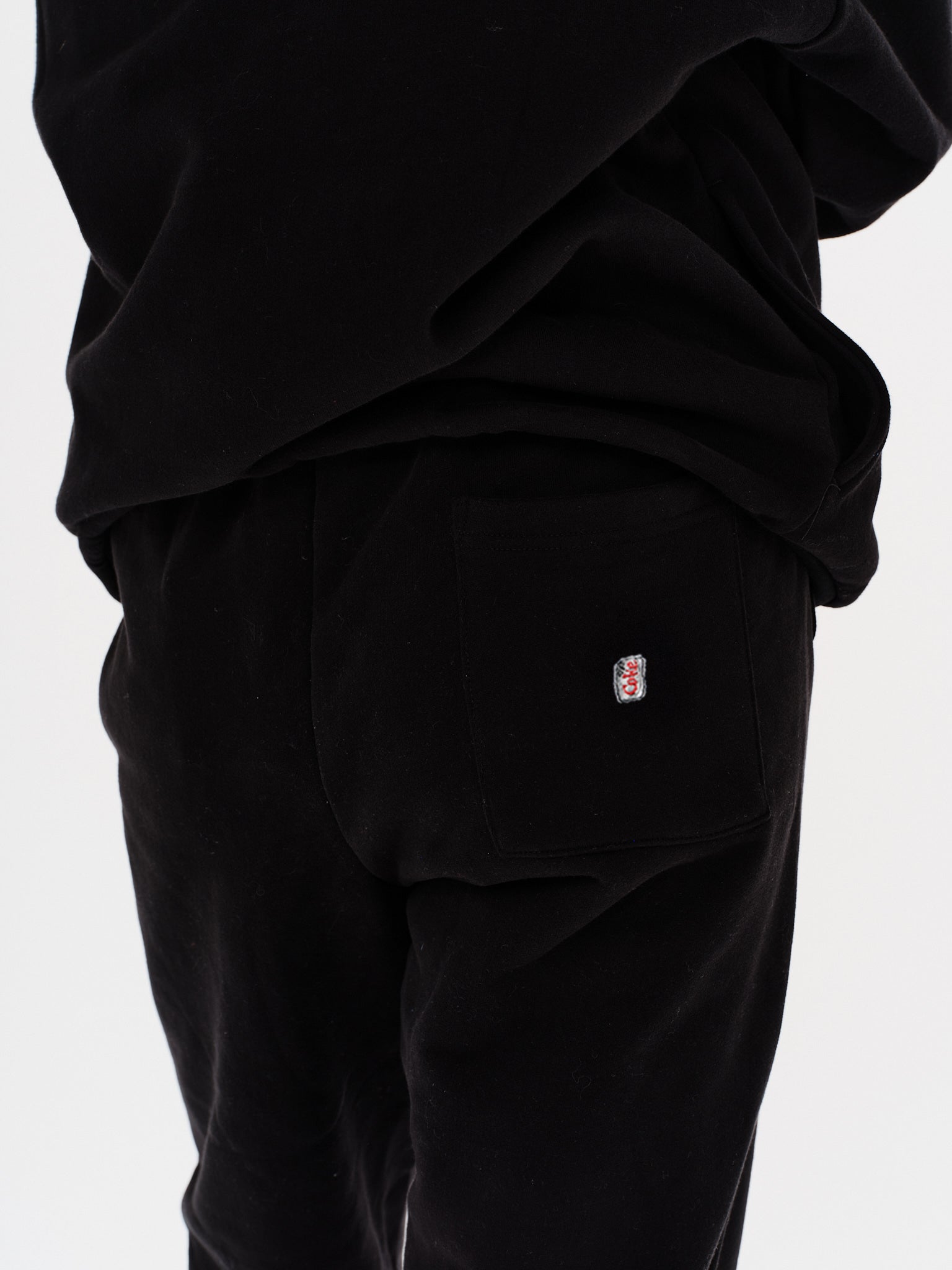 Woman wearing black pants with a Diet Coke embroidery