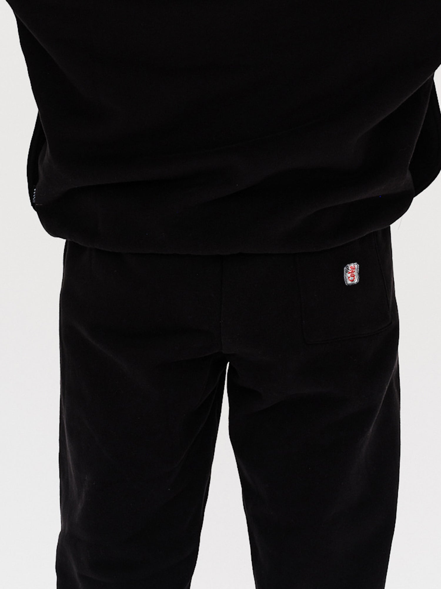 Woman wearing black pants with a Diet Coke embroidery