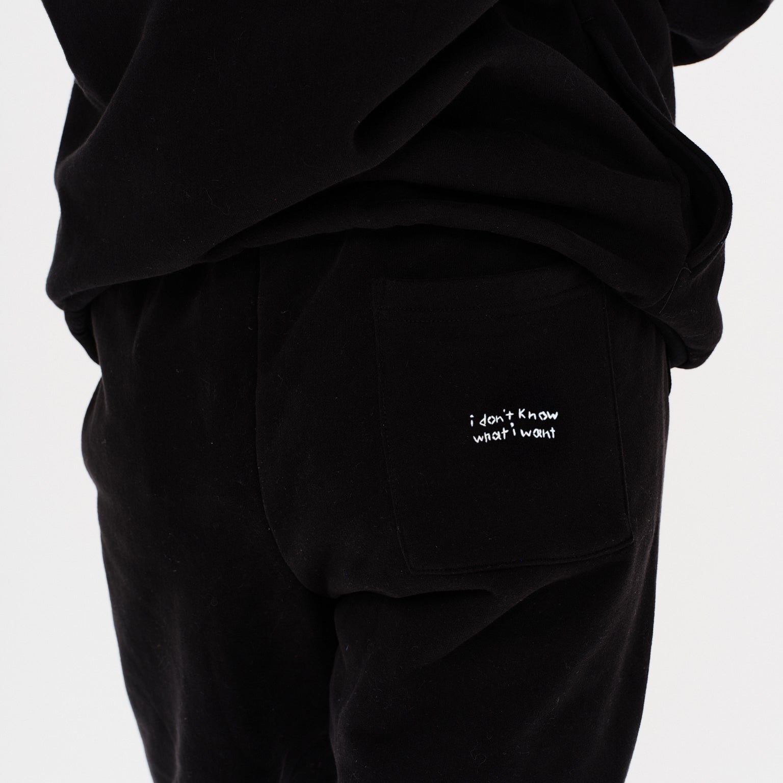 Woman wearing black pants with I dont know what i want embroidery