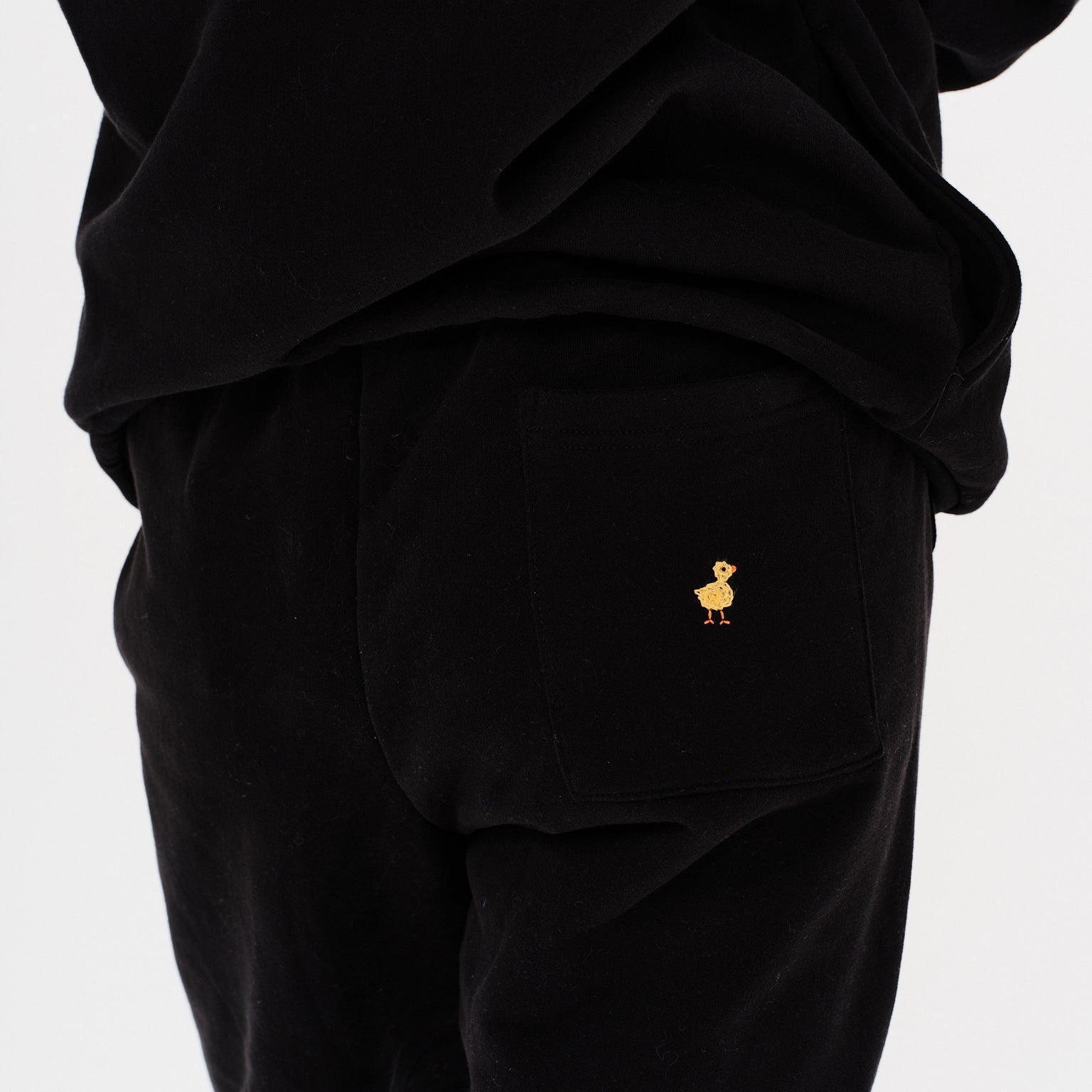 Woman wearing black pants with duck embroidery