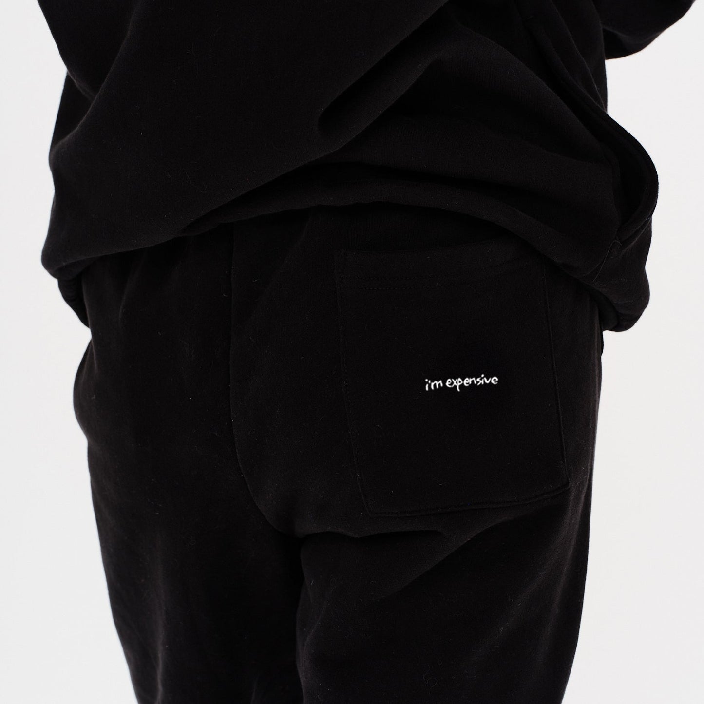Woman wearing black pants with I'm Expensive embroidery