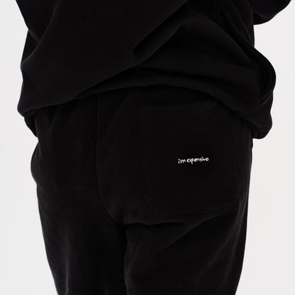 Woman wearing black pants with I'm Expensive embroidery