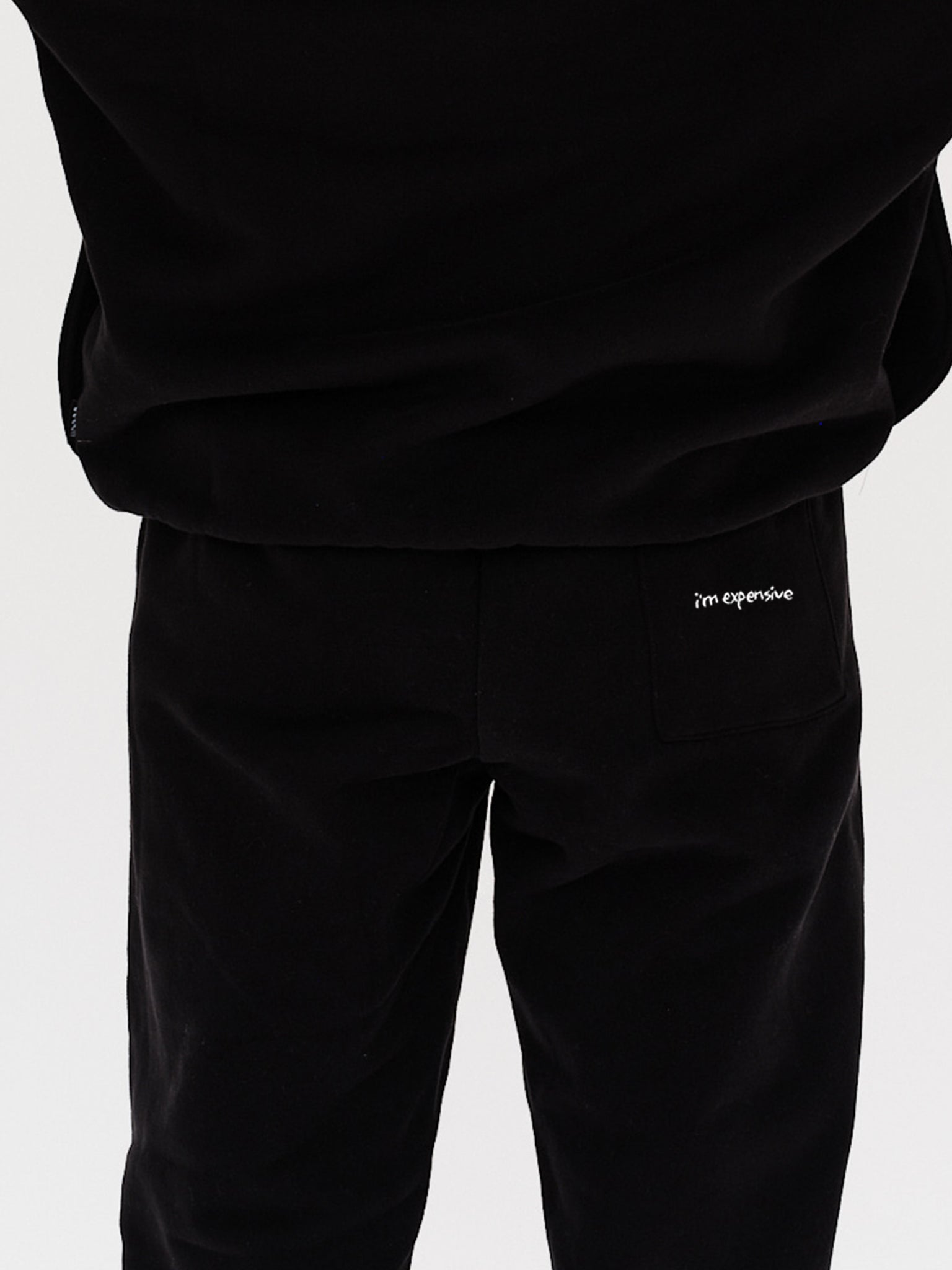 Woman wearing black pants with I'm Expensive embroidery