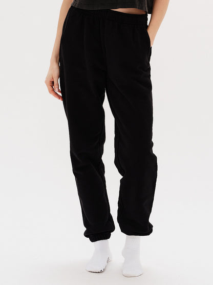 Woman wearing black pants with I'm Expensive embroidery
