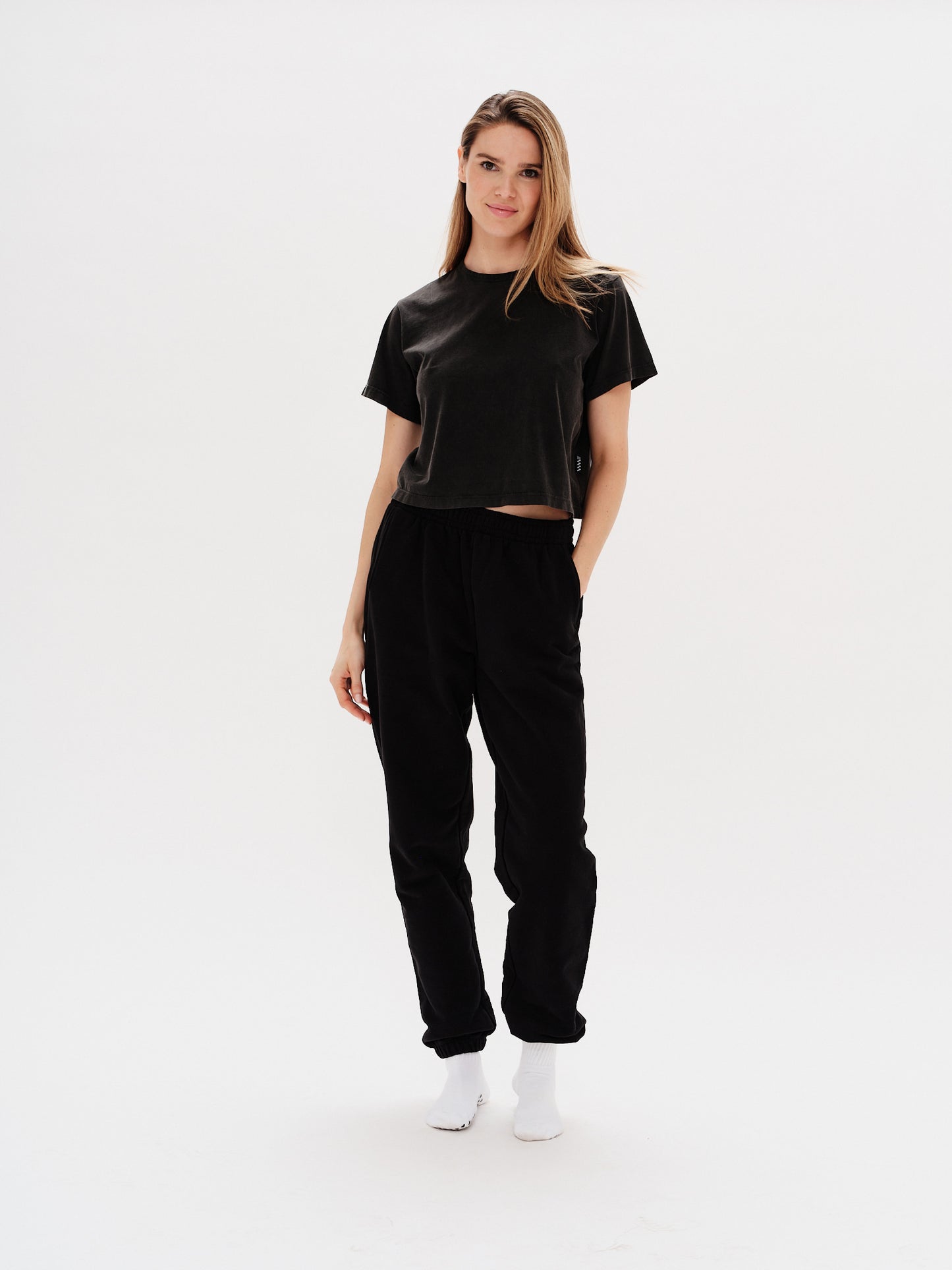 Woman wearing black pants with I'm Expensive embroidery