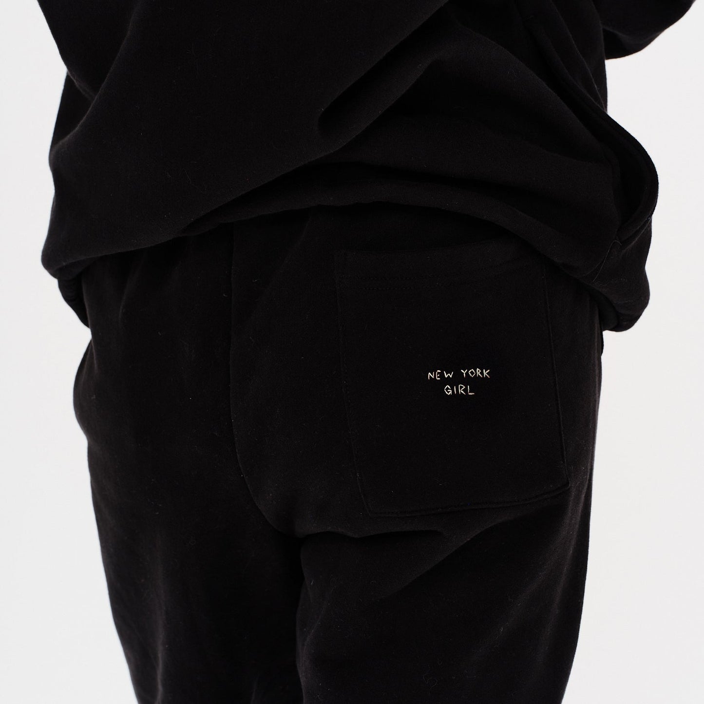 Woman wearing black pants with New York Girl embroidery