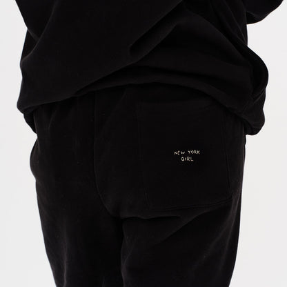 Woman wearing black pants with New York Girl embroidery