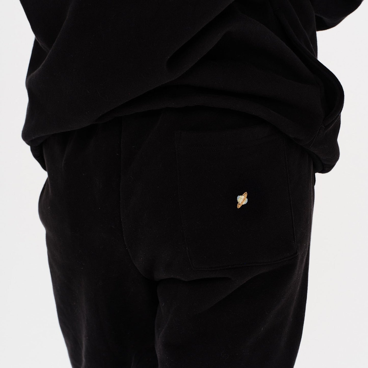 Woman wearing black pants with a planet embroidery