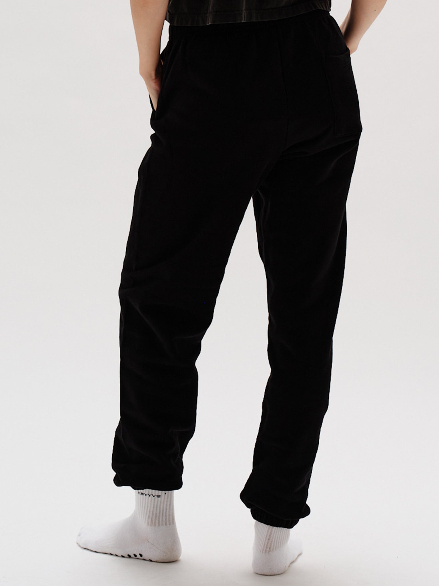 Woman wearing black pants with West Village embroidery