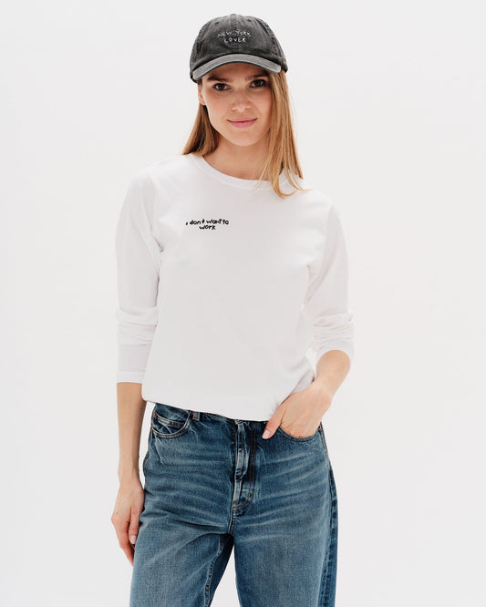 Woman wearing a white long-sleeve t-shirt with a i don´t want to work embroidery
