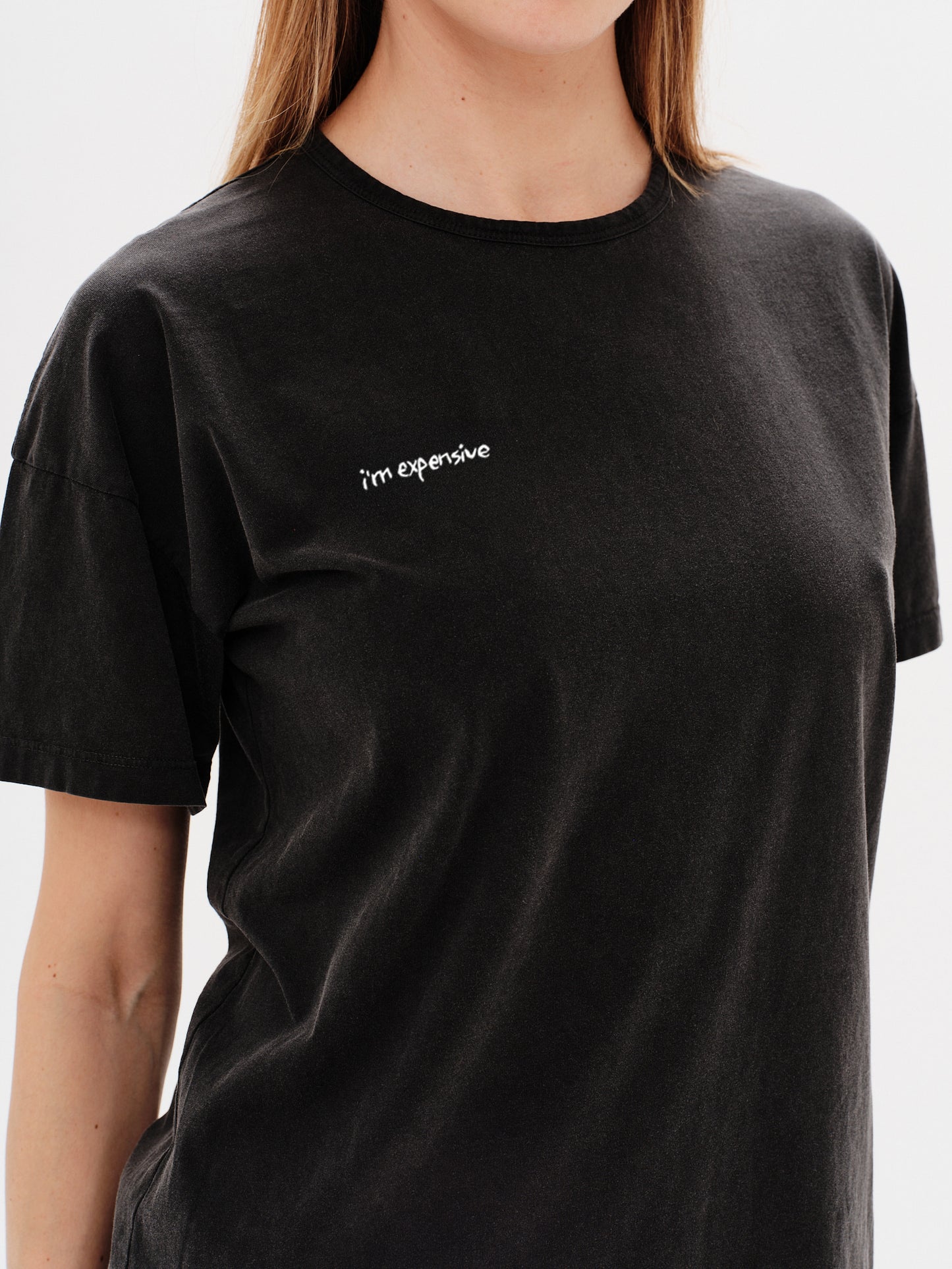 Woman wearing a black t-shirt with a i'm expensive embroidery
