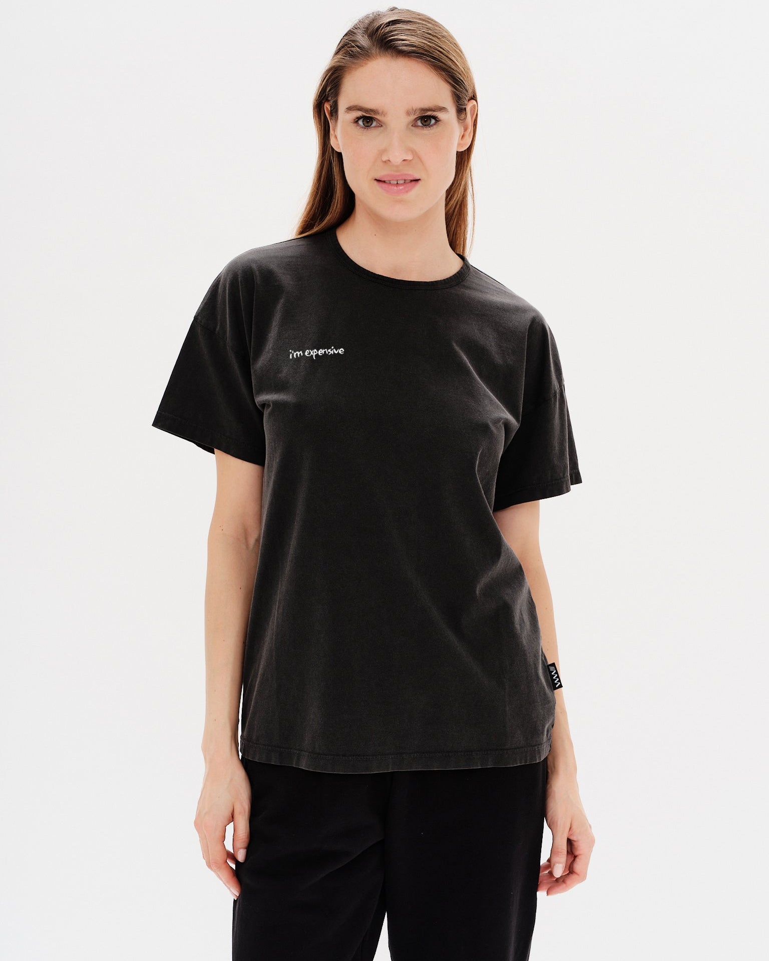 Woman wearing a black t-shirt with a i'm expensive embroidery