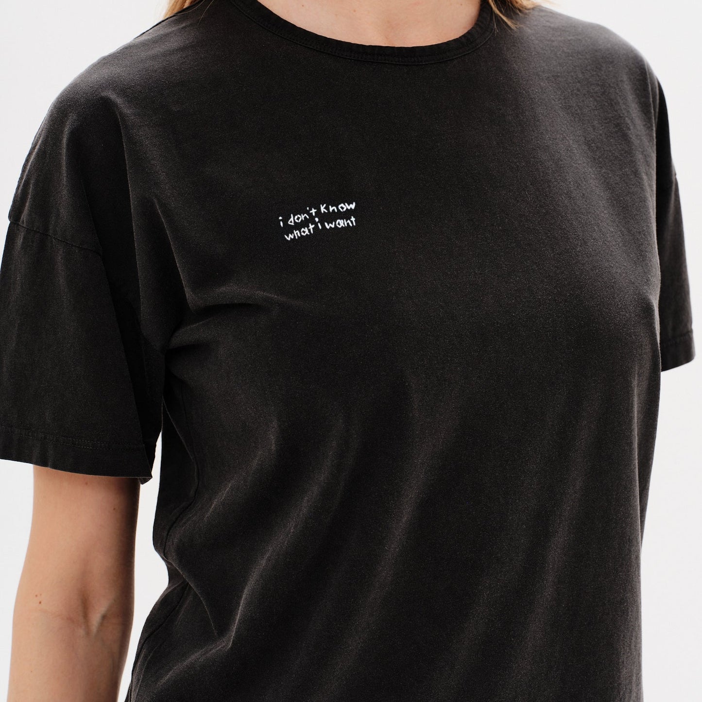 Woman wearing a black t-shirt with a i don't know what i want embroidery