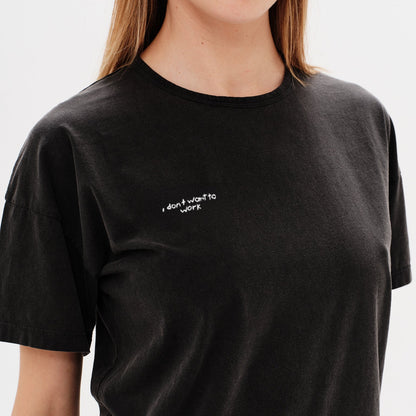 Woman wearing a black t-shirt with a i don't want to work embroidery