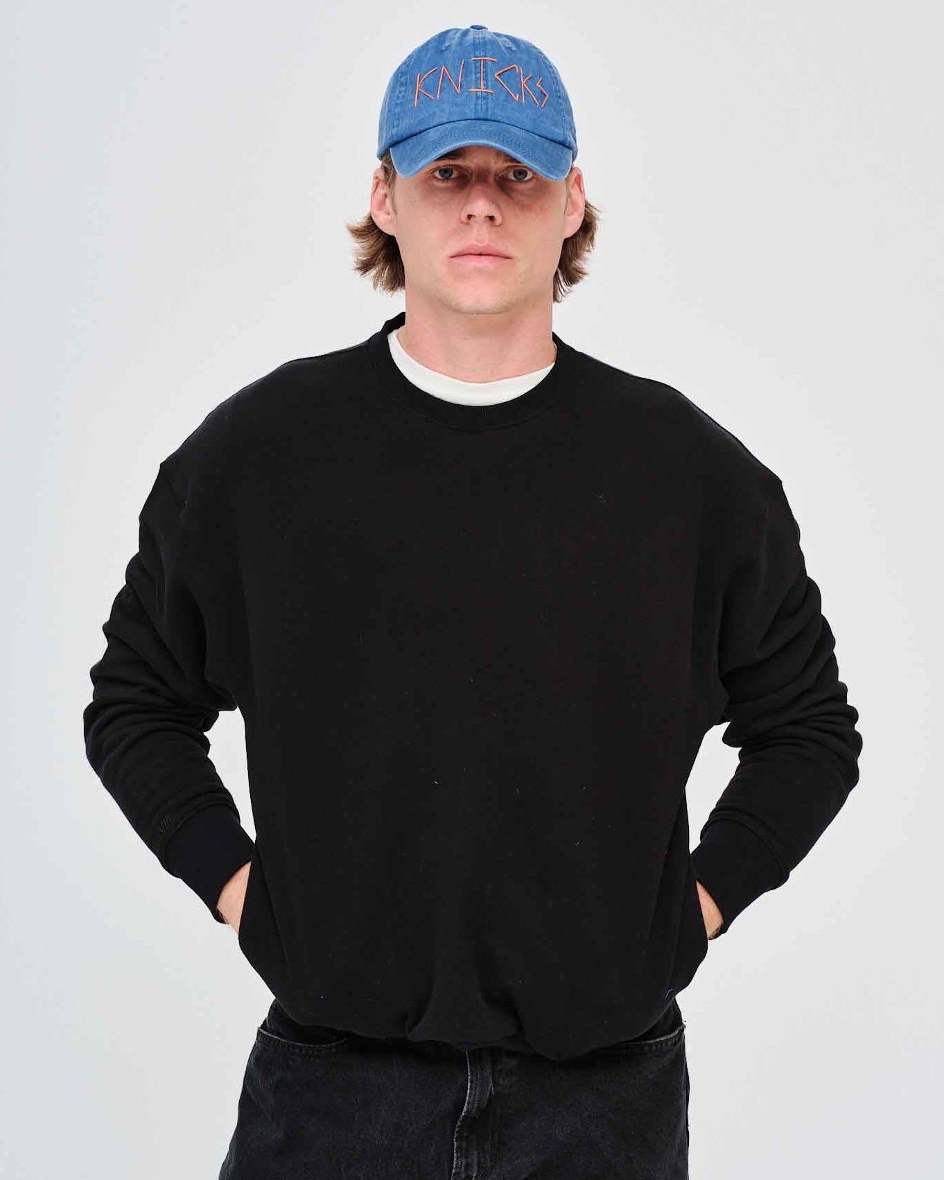 Man wearing a black sweatshirt and blue cap
