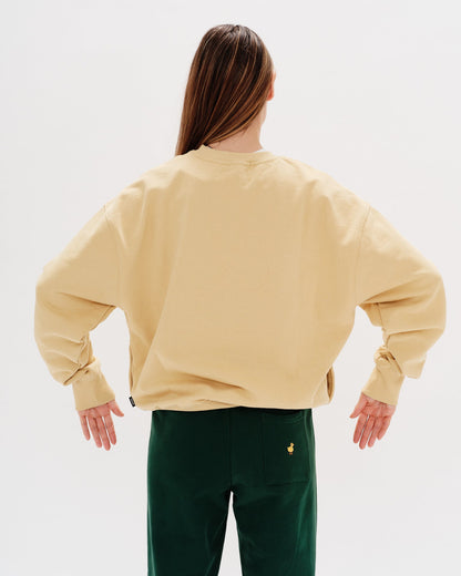 Person wearing a beige sweatshirt and green pants