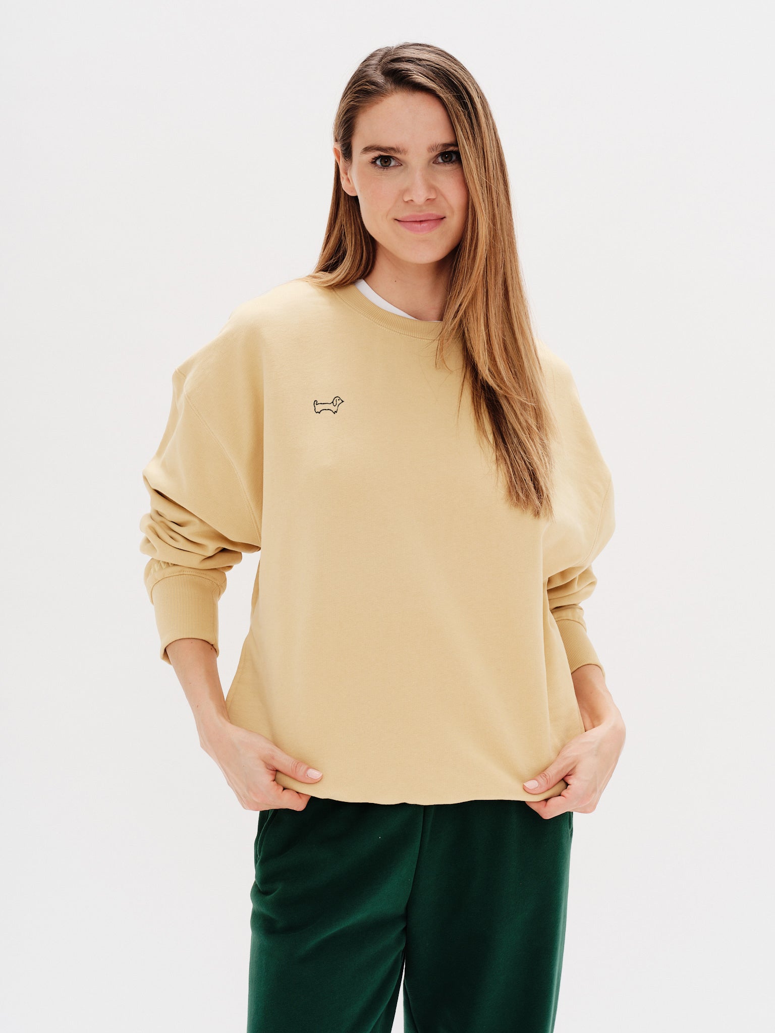 Woman wearing a yellow sweatshirt with a wiener dog embroidery