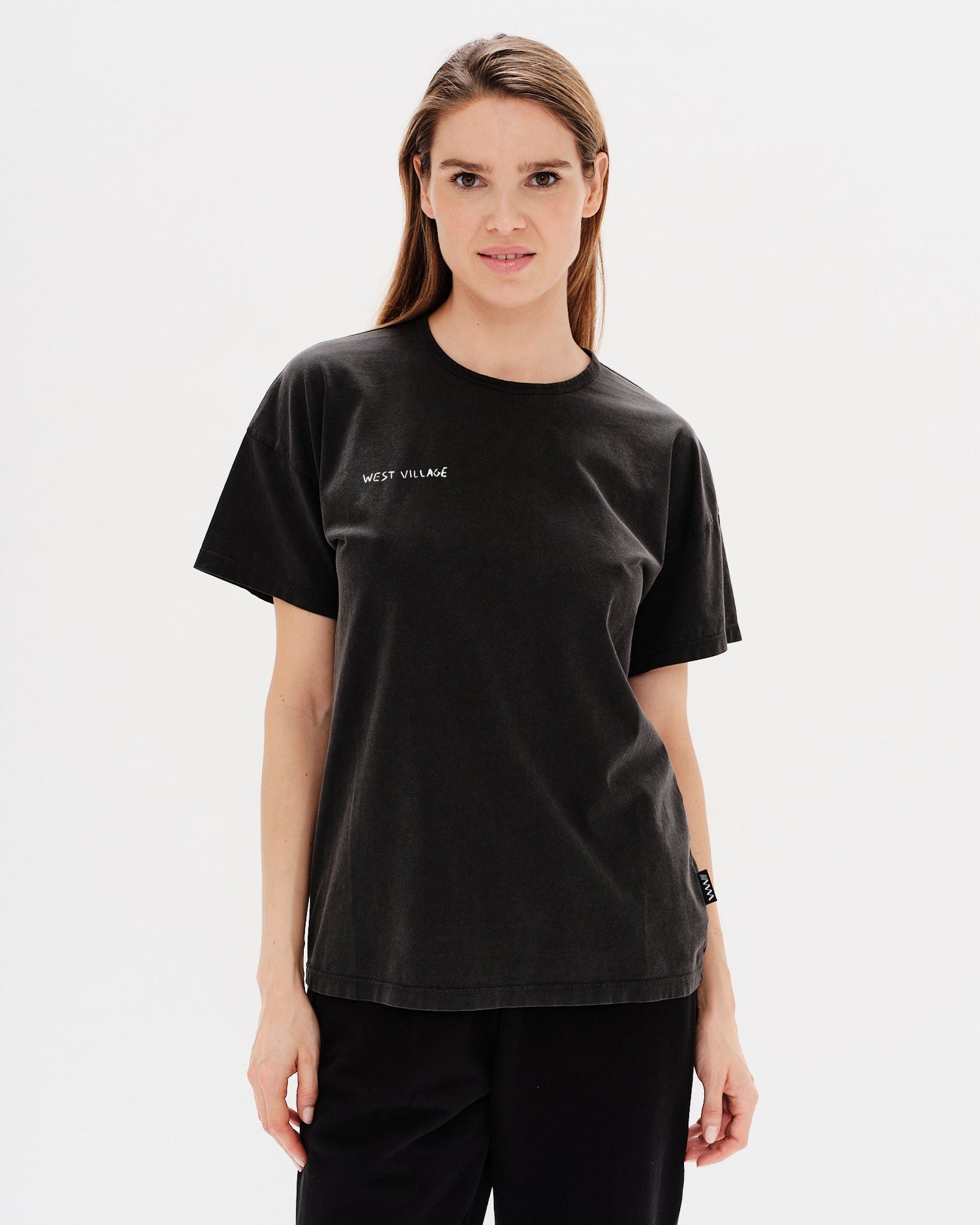 Woman wearing a black t-shirt with West Village embroidery