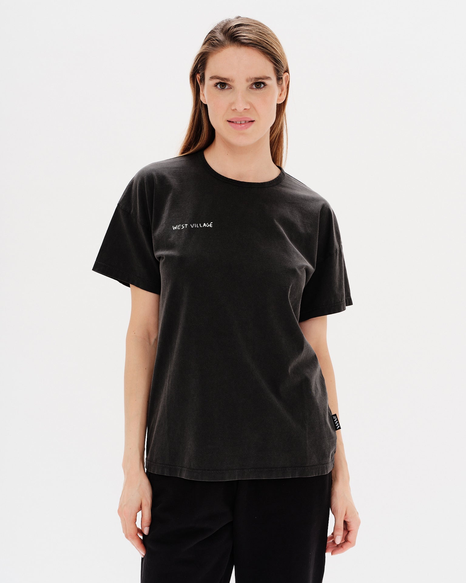 Woman wearing a black t-shirt with West Village embroidery