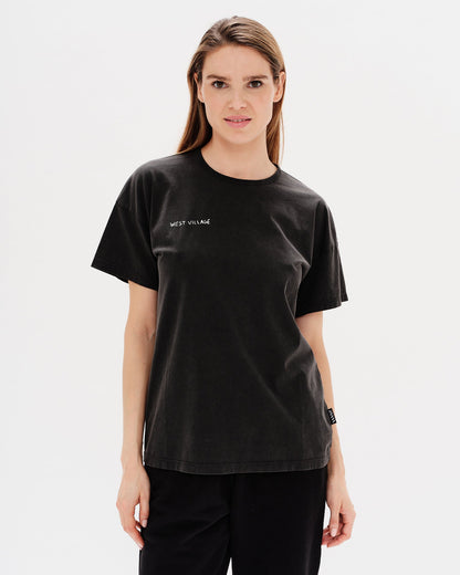 Woman wearing a black t-shirt with West Village embroidery