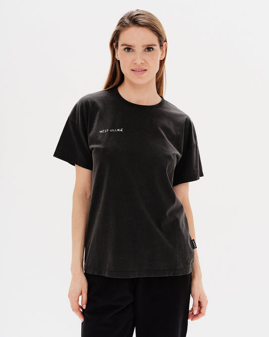 Woman wearing a black t-shirt with West Village embroidery